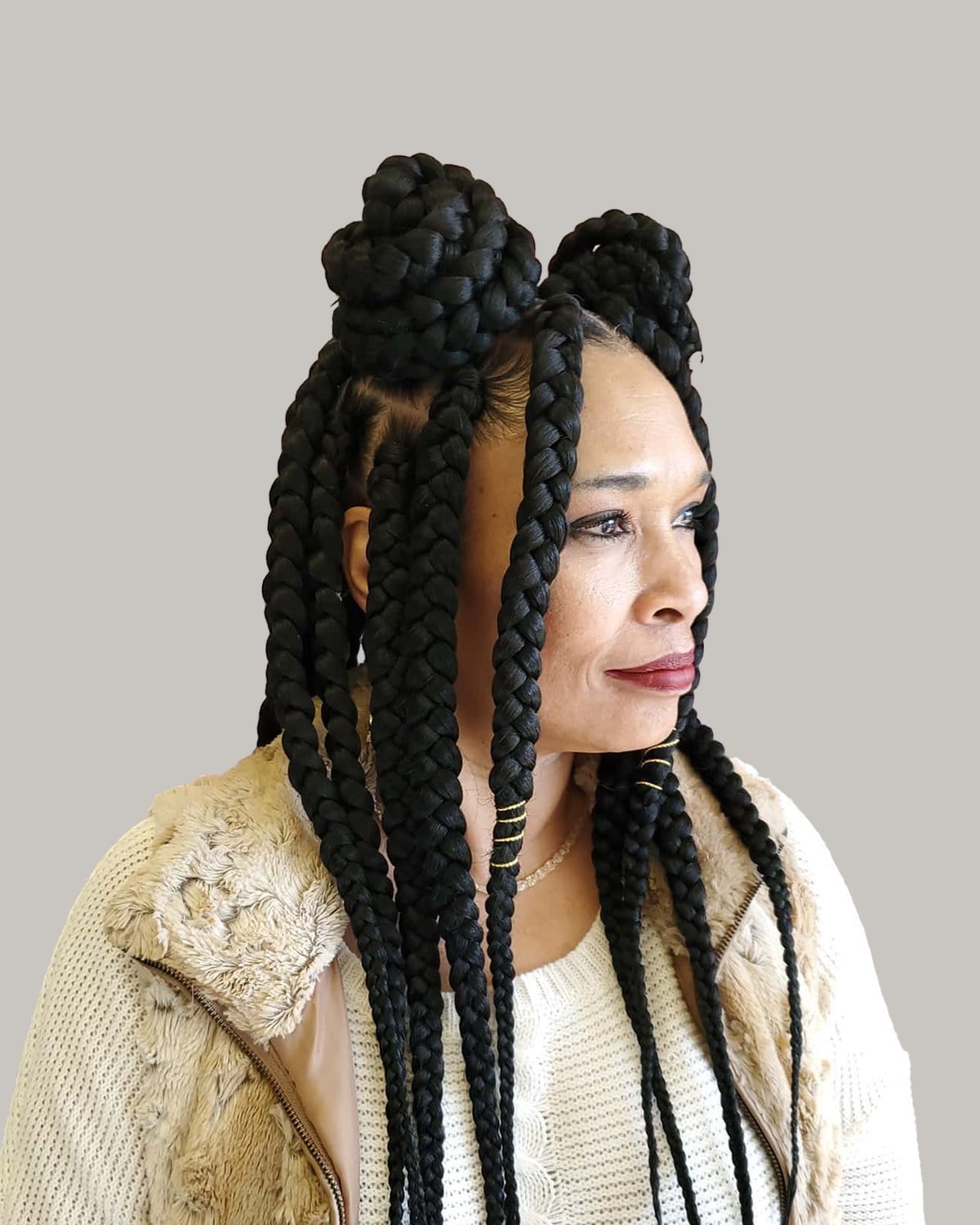 Woman in a cream sweater and faux-fur vest with two jumbo braid space buns