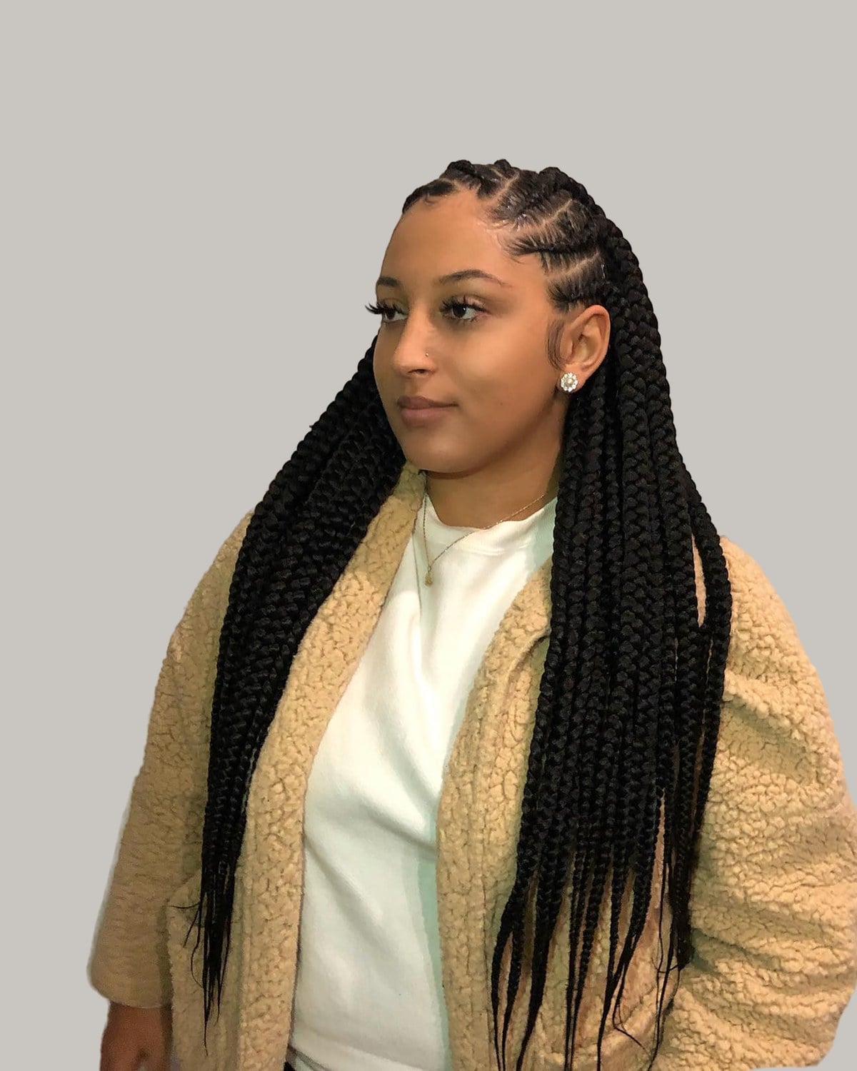 Woman in a cream sherpa jacket with jumbo tribal braids, in three-quarter view