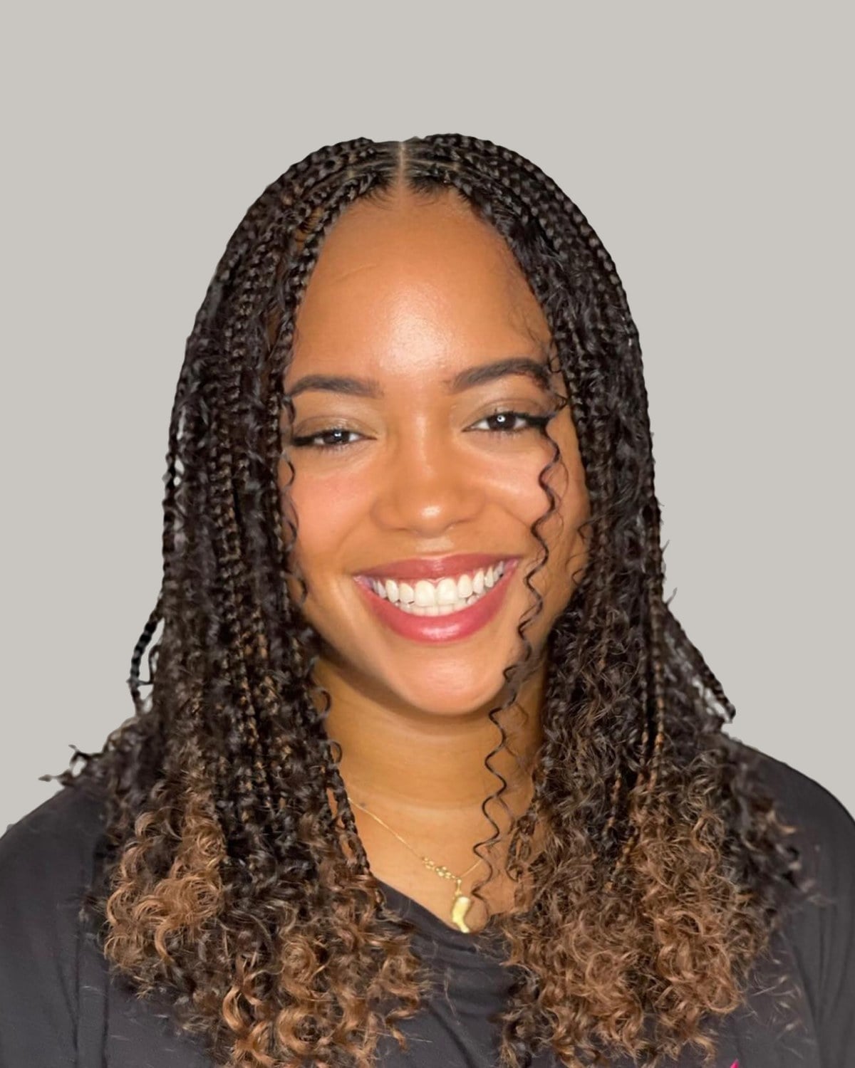 Smiling woman with chest-length ombré knotless braids and curly ends