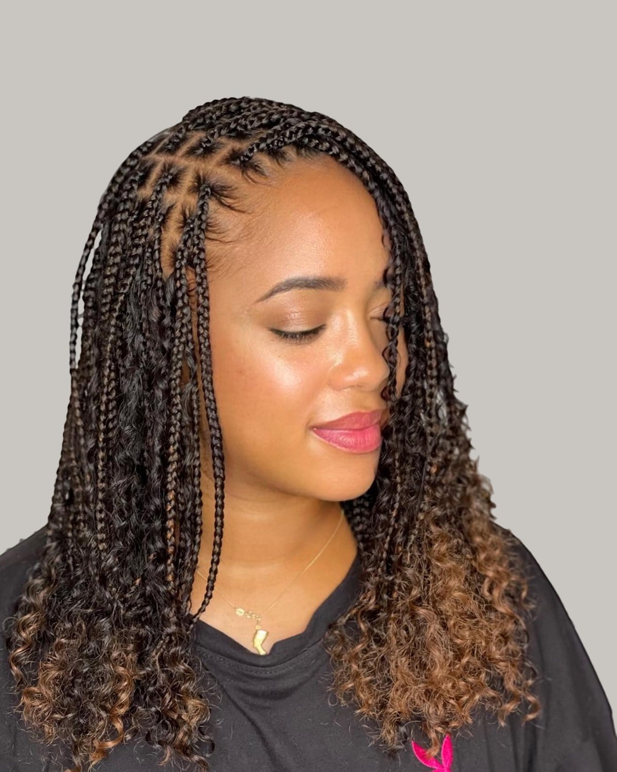Woman in a black T-shirt with brown ombré knotless braids and curly ends