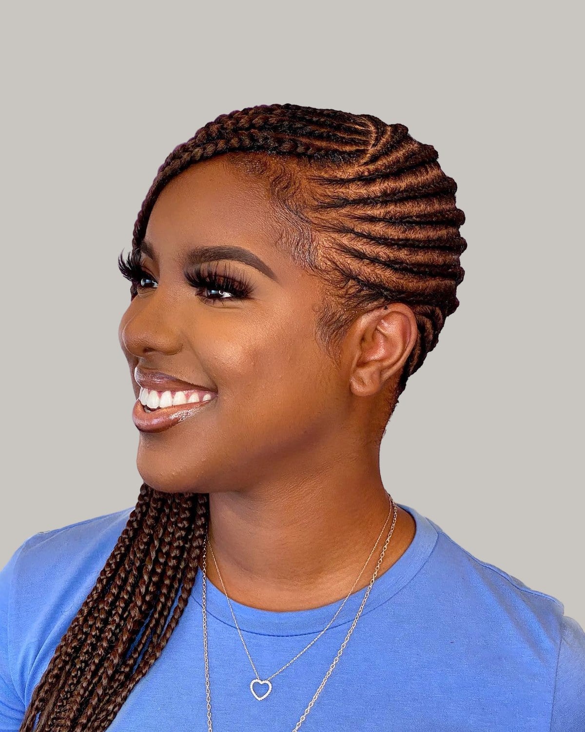 Woman in a blue T-shirt in three-quarter view, copper-brown lemonade braids