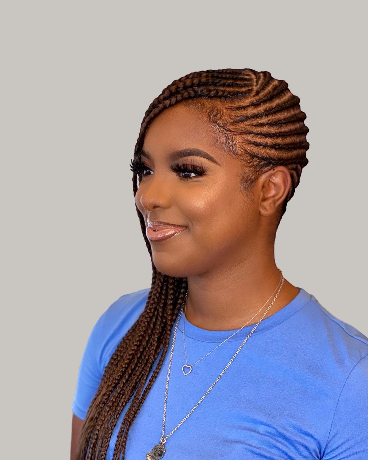 Smiling woman in a blue T-shirt with copper-brown lemonade braids