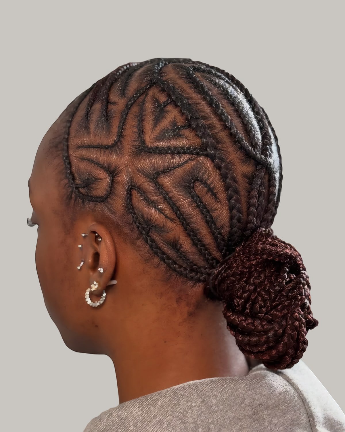 Woman seen from the side with stitch braids curving back into a low bun