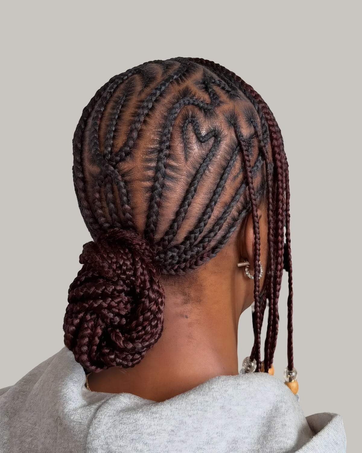 Back view of stitch braids with a heart design and a low bun over a gray hoodie