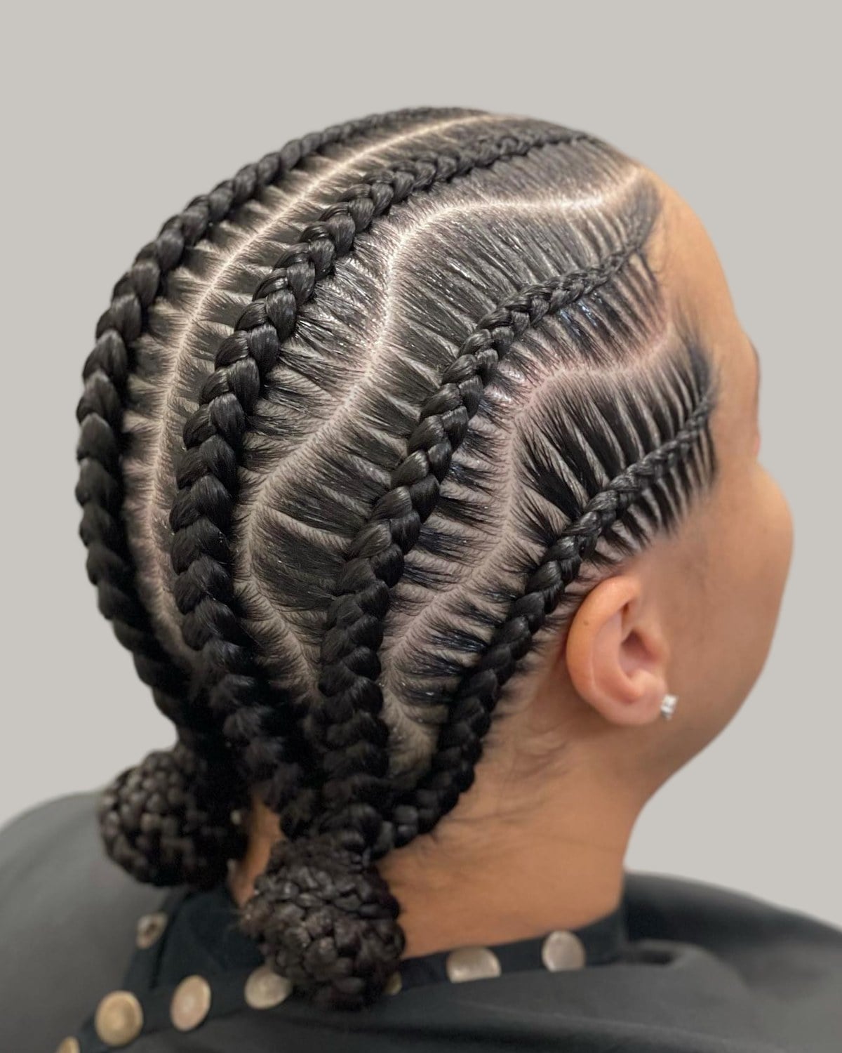 Wavy stitch braids gathered into two low buns, seen from behind at an angle
