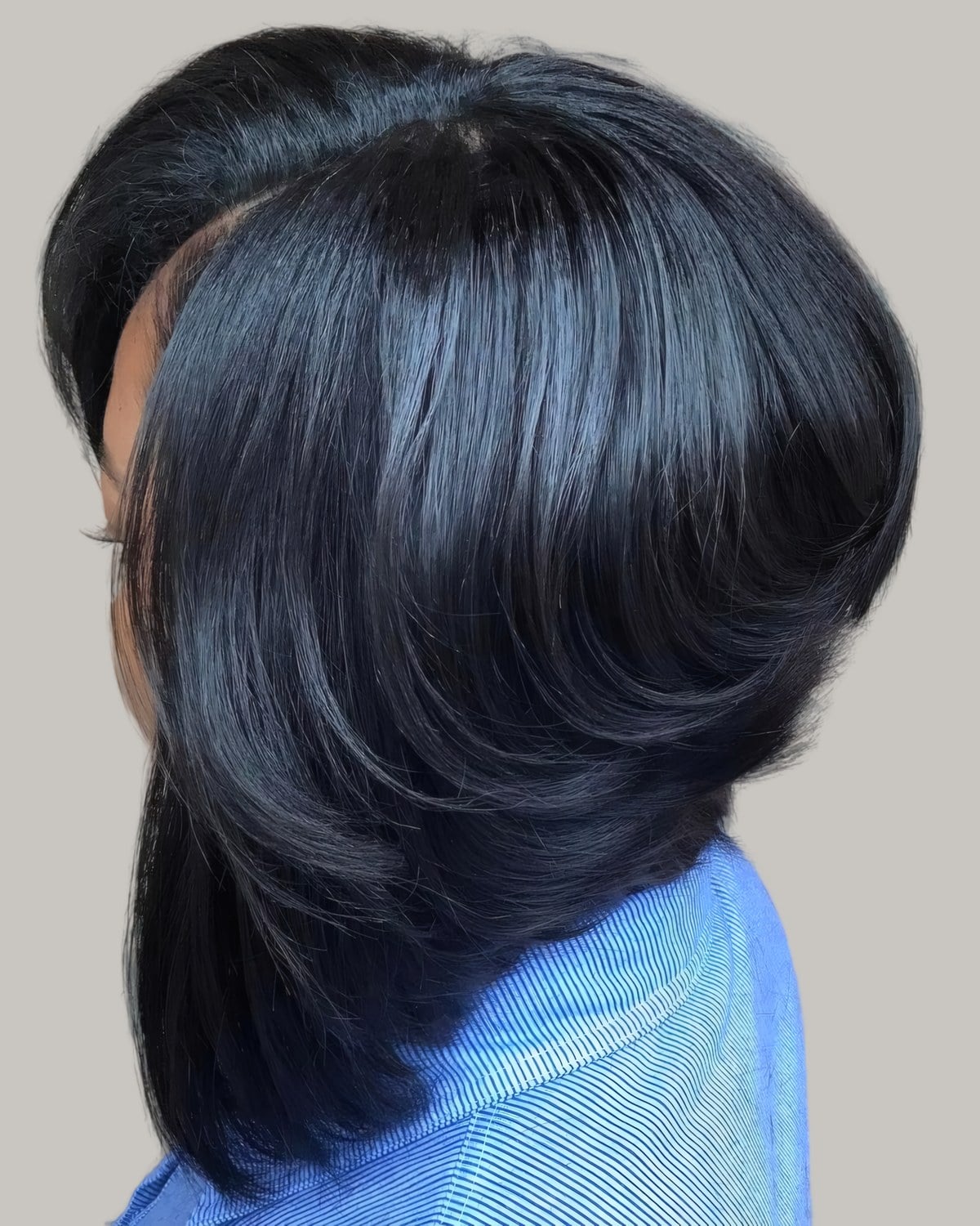 Woman with a glossy black layered bob seen from the side