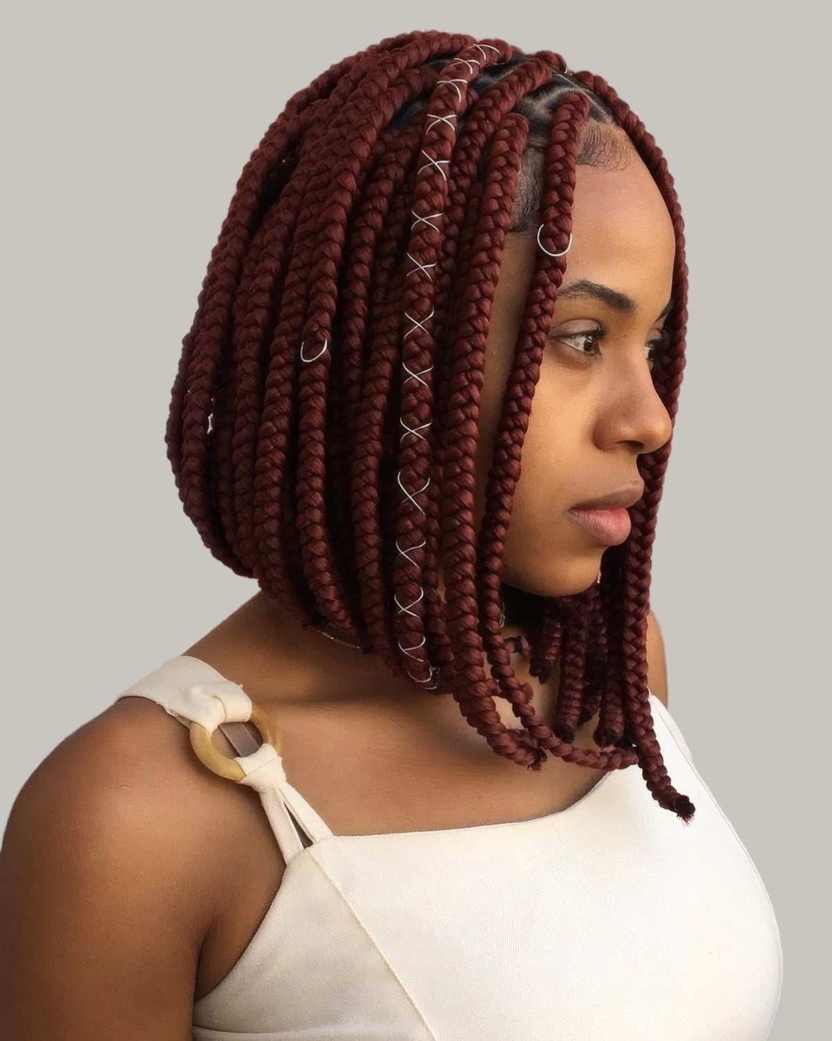 Woman with burgundy box braids in a bob, looking to the side