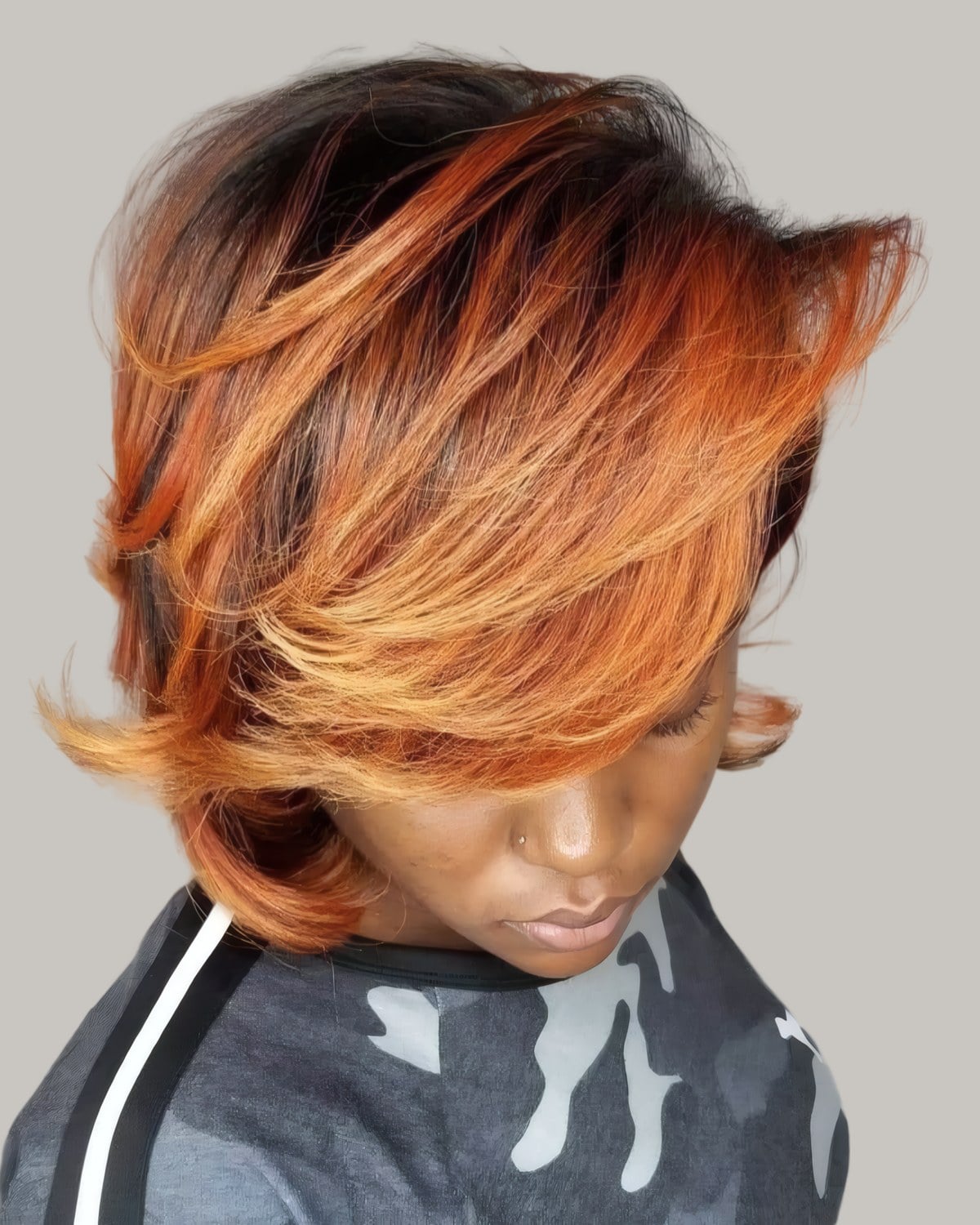 Woman with a copper bob with dark roots, looking down