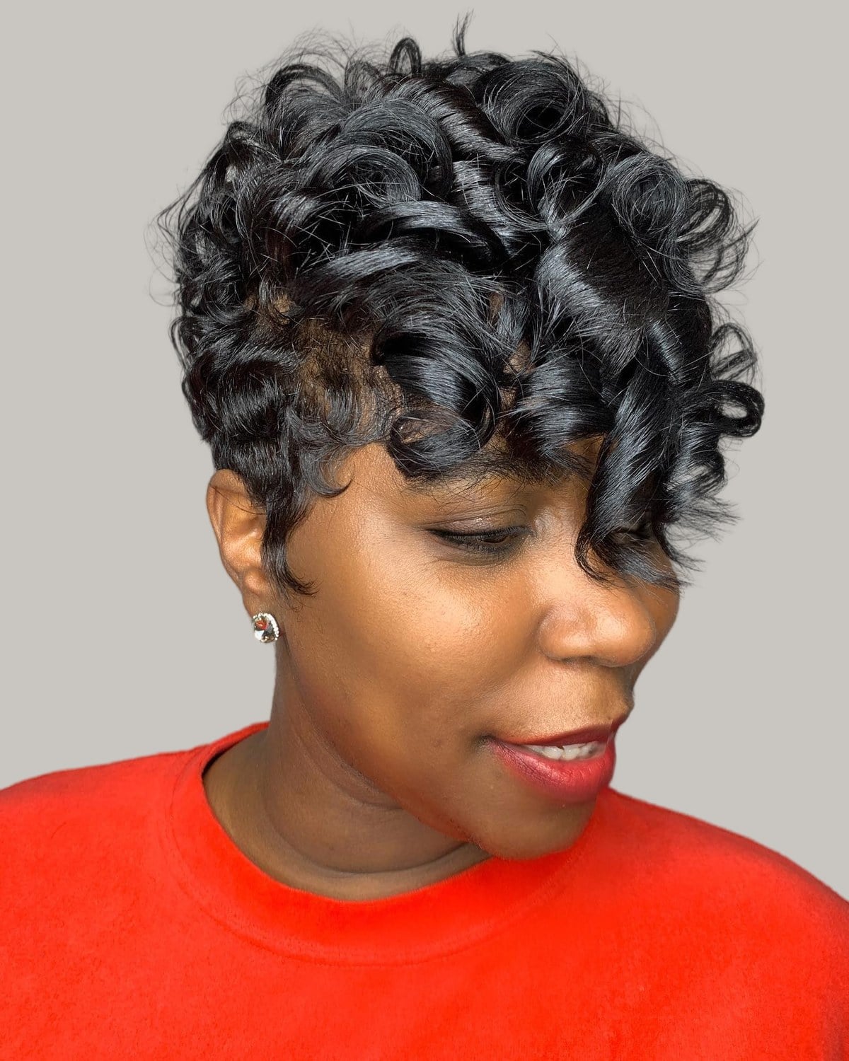 Woman with a black curly pixie, curls falling onto her forehead