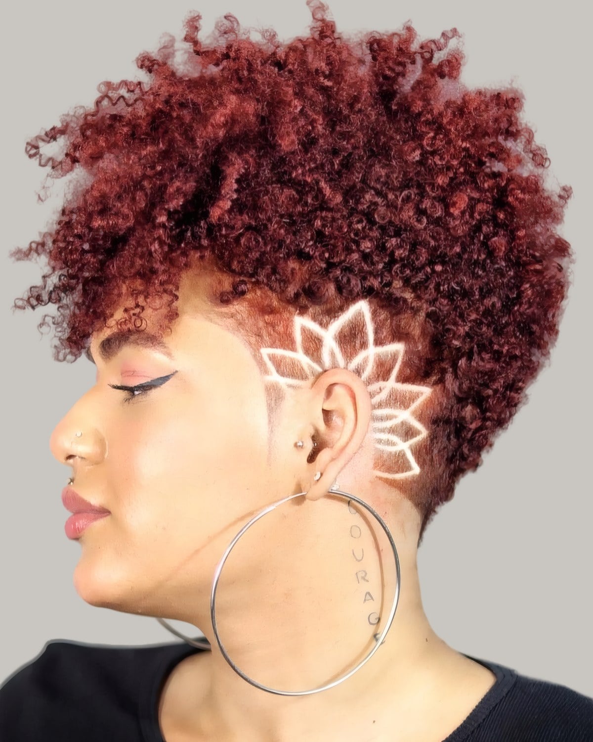 Woman with red curls and a flower design shaved into the side