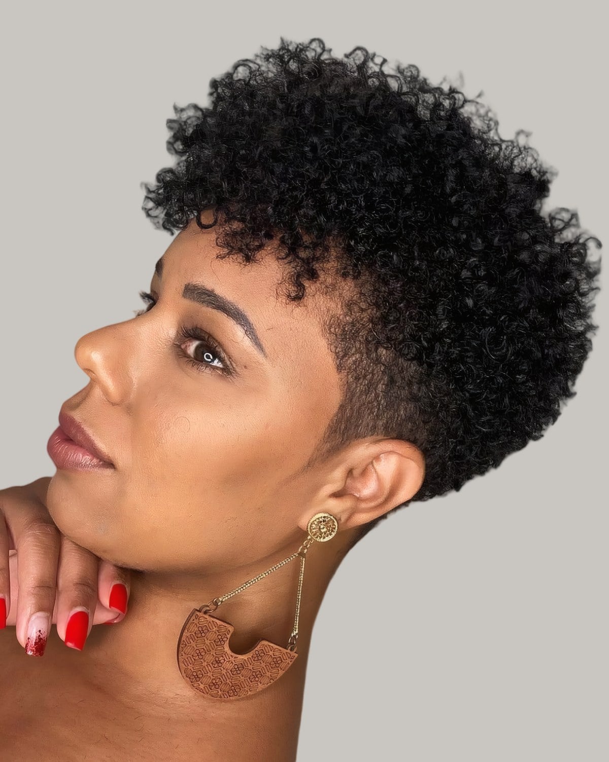 Woman with a black curly mohawk and a faded side, looking over her shoulder