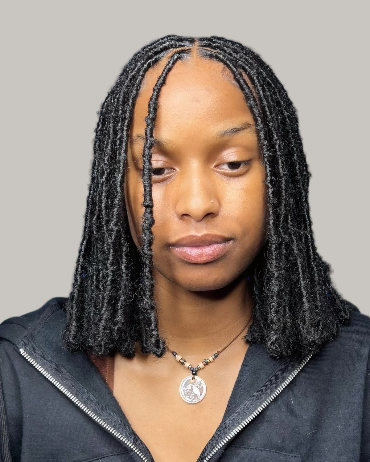 Woman with thin faux locs to the shoulder and a center part