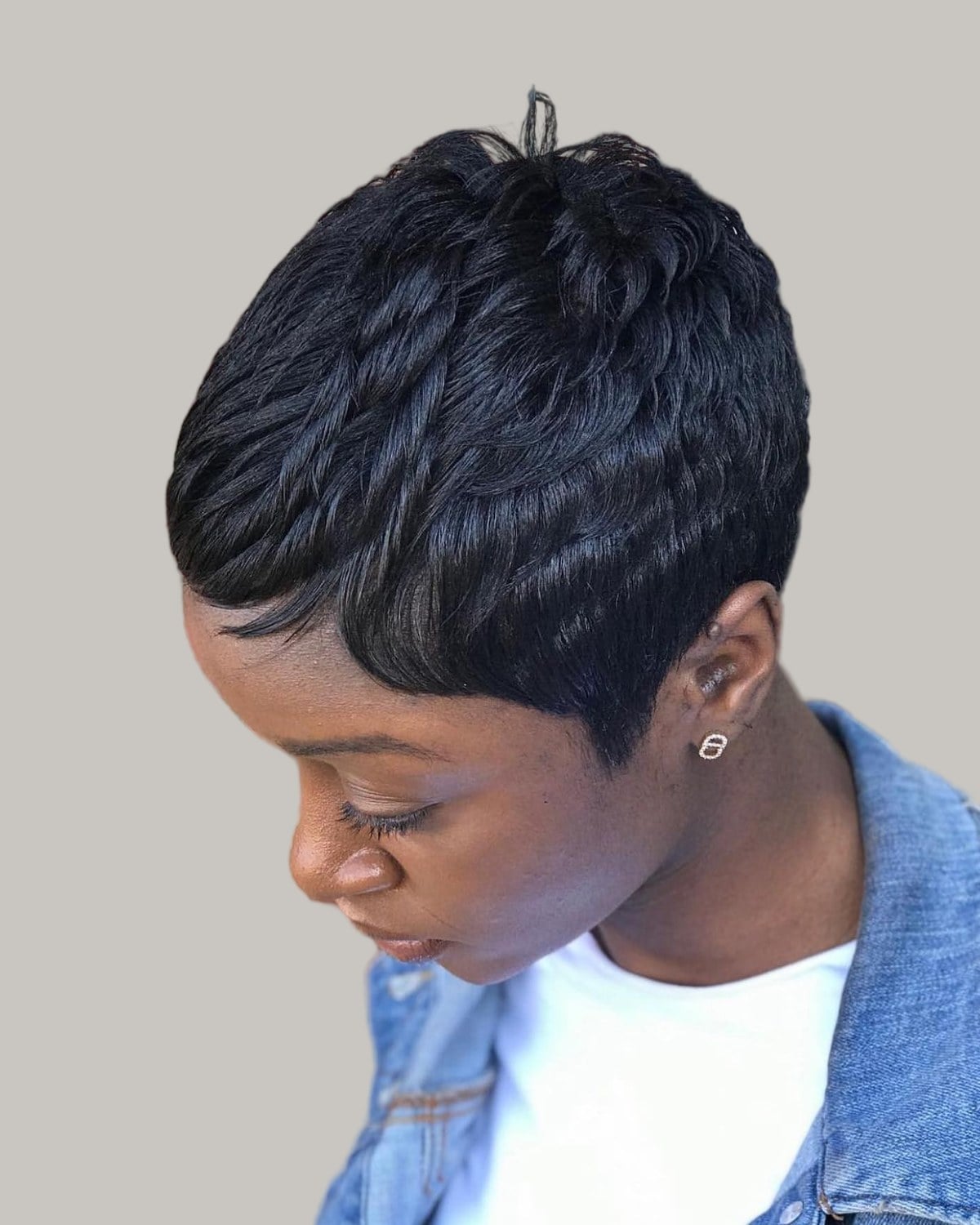Woman with a short black textured crop, looking down