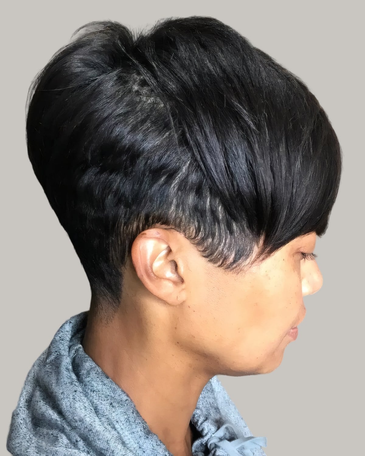 Woman with a sleek black pixie, a long side-swept top and a short nape