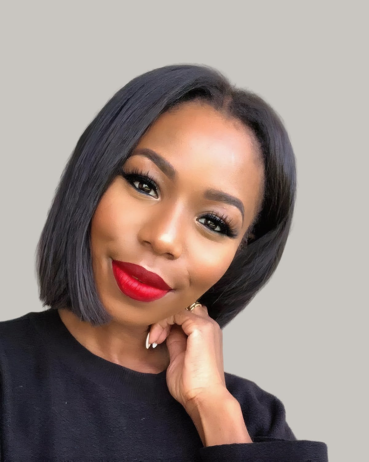Smiling woman with a sleek black bob, hand at her chin