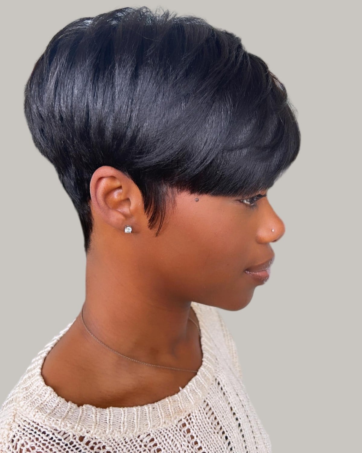 Woman with a glossy black pixie, the top rounded over a close nape