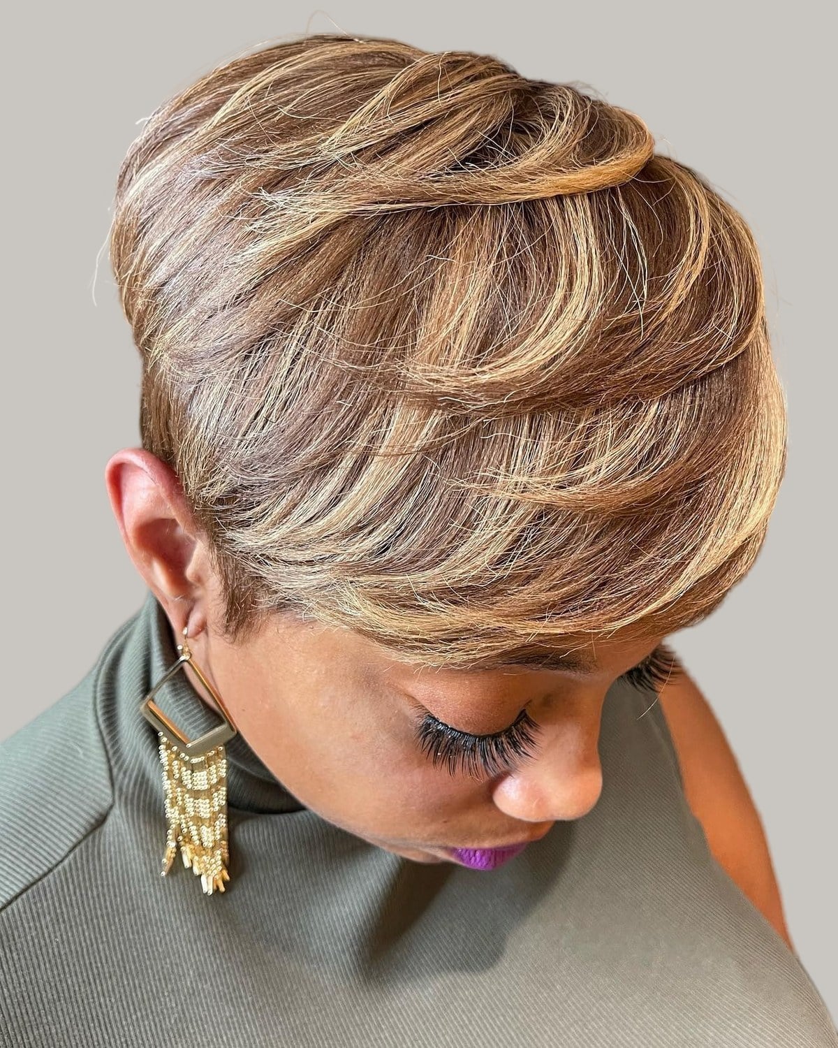 Woman with a sculpted short cut in blonde and brown, seen from the side