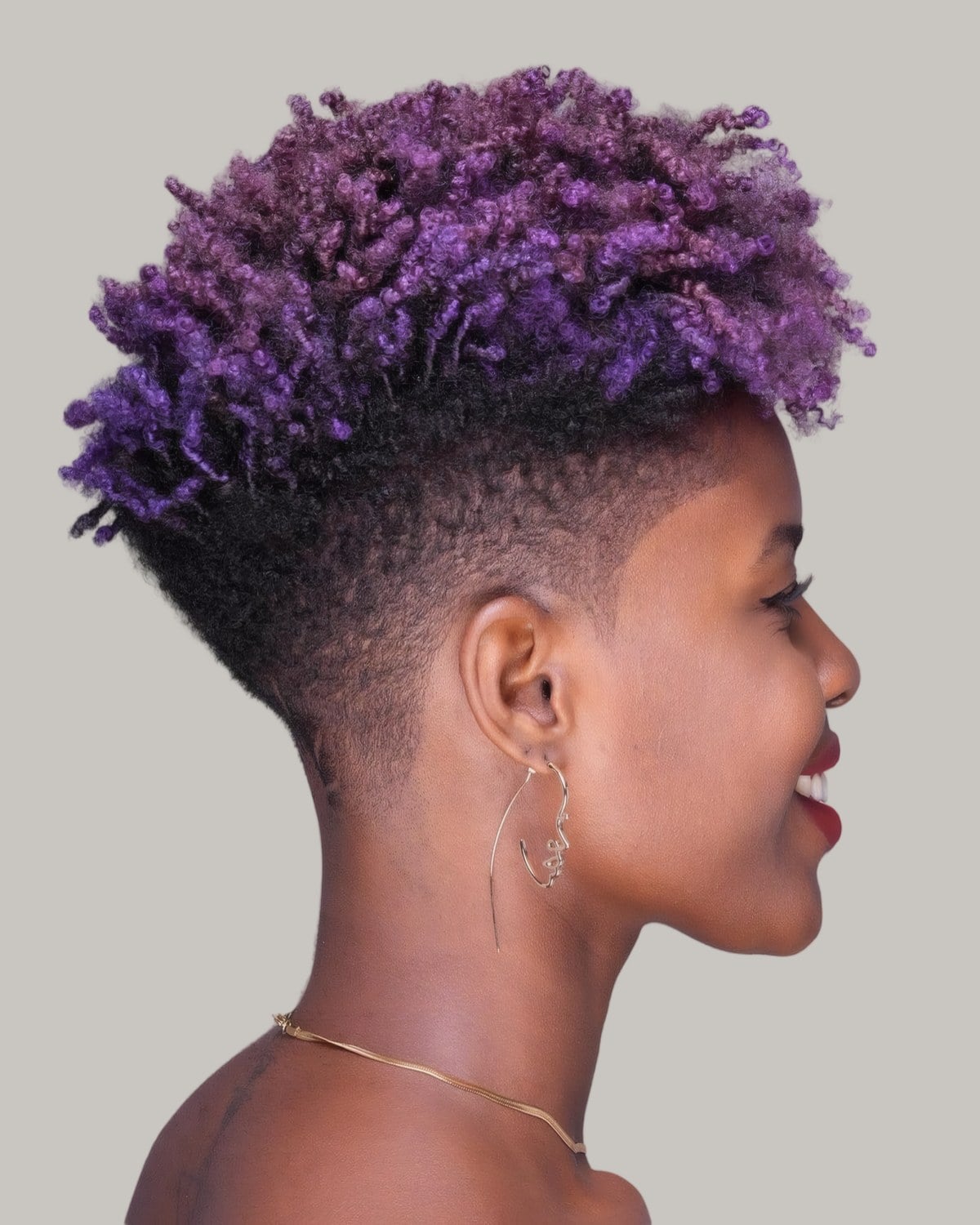 Woman with violet coils on top and a close taper, seen in profile
