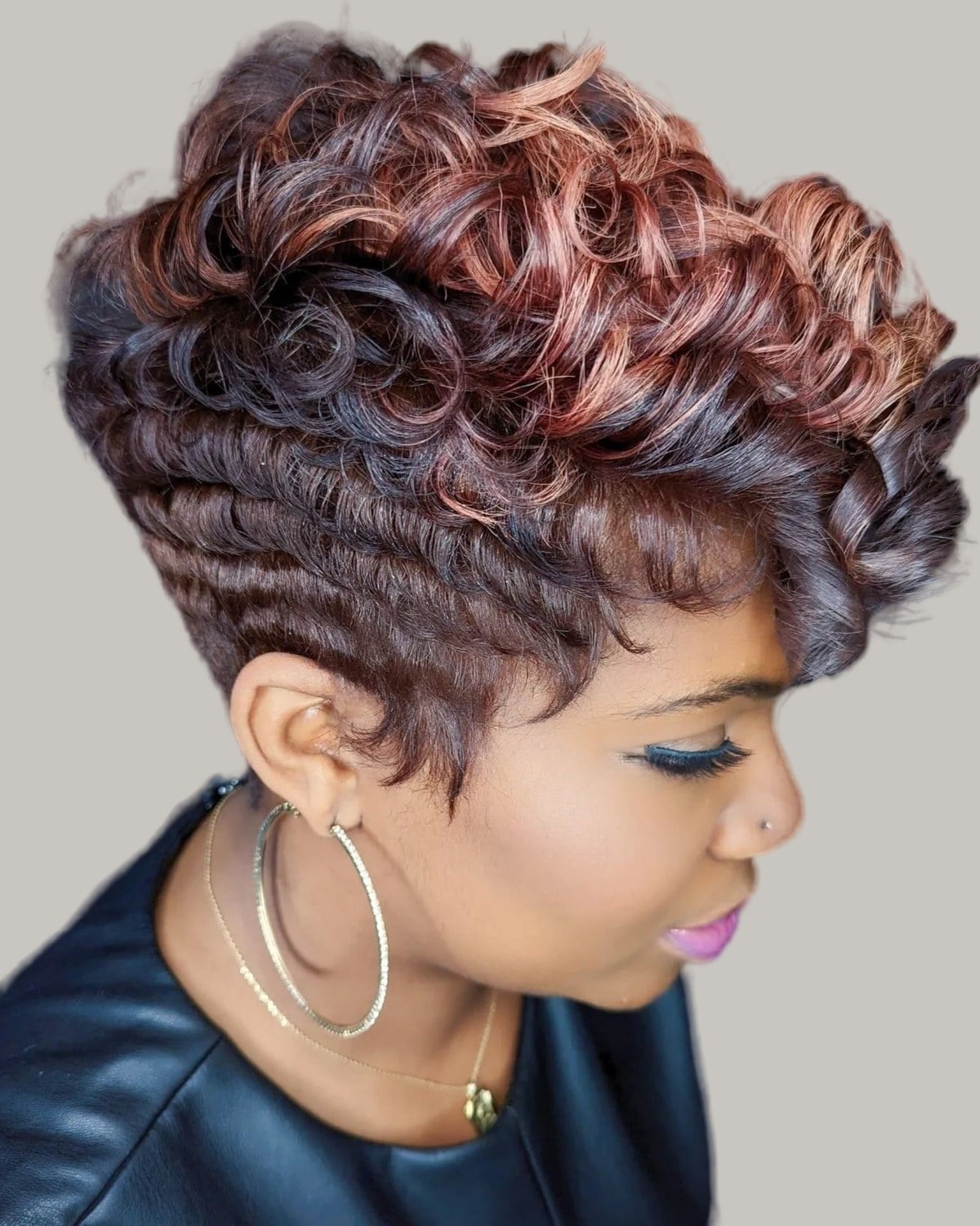 Woman with short rose-brown waves and hoop earrings