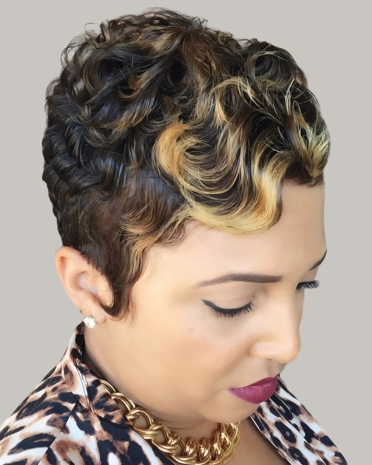 Woman with short dark curls with golden highlights, leopard print top