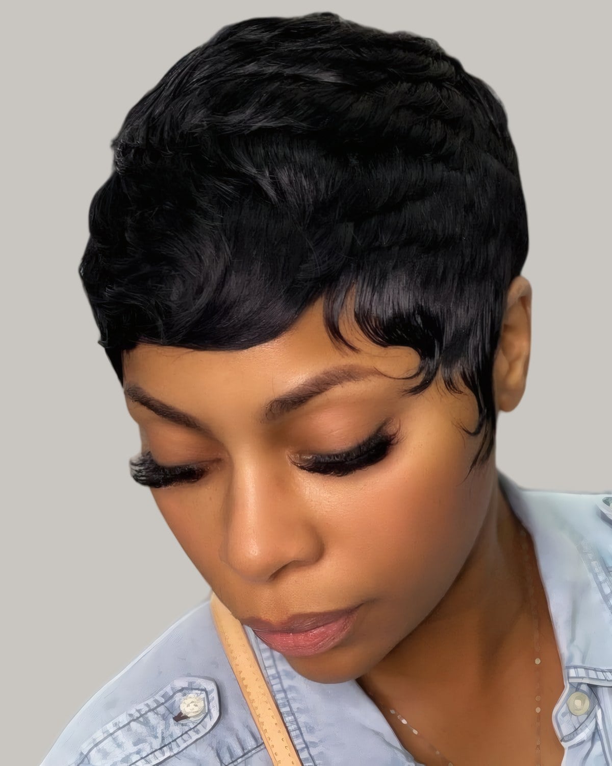 Woman with a short black waved pixie, looking down