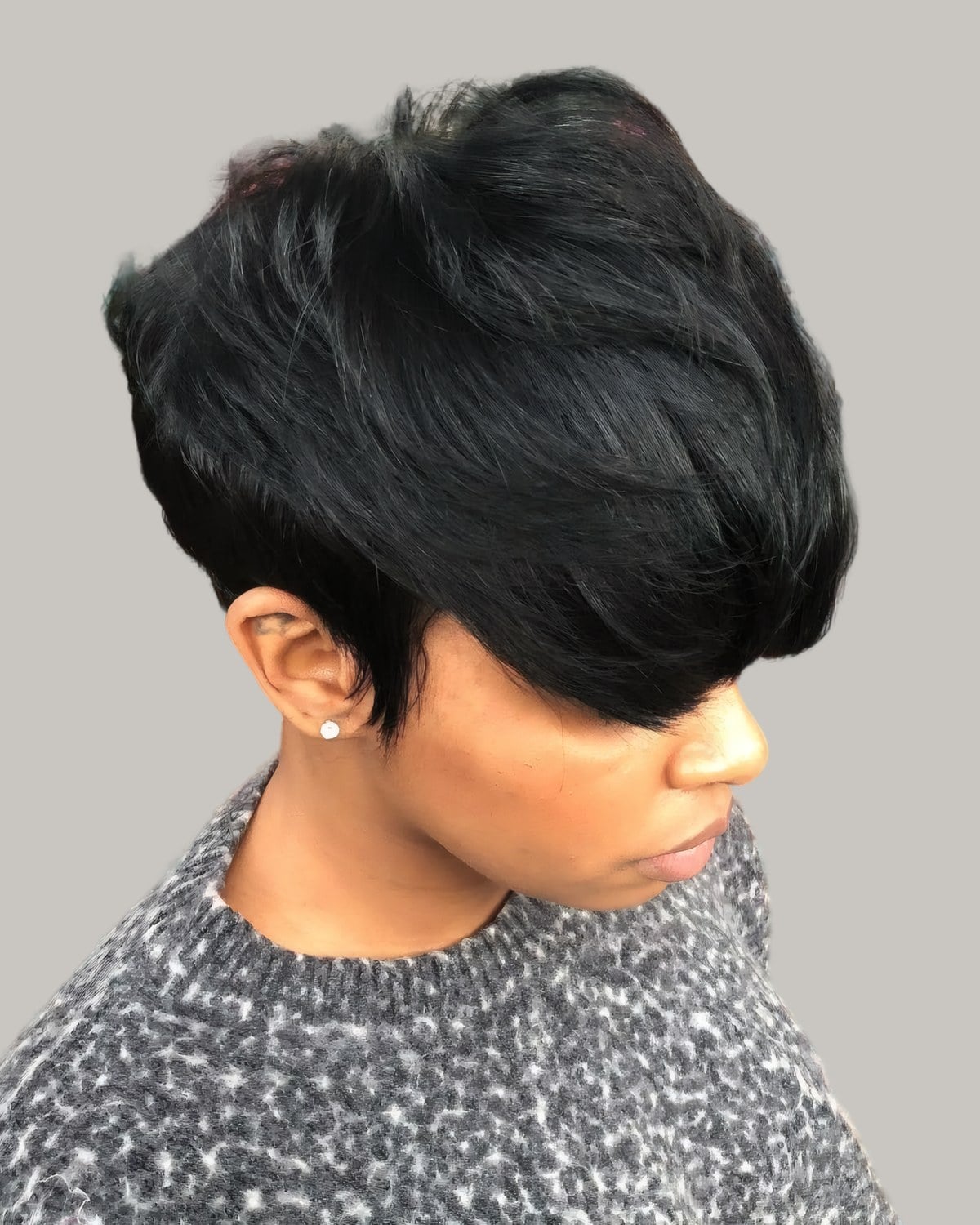 Woman with a sleek black short cut, a long fringe falling over one eye