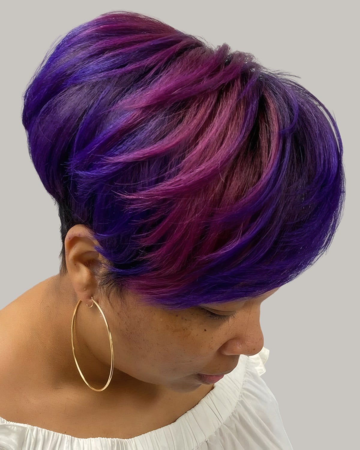 Woman with a short purple bob and hoop earrings