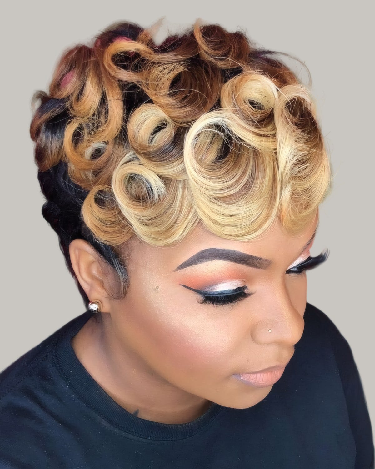 Woman with blonde pin curls and dark roots, looking down