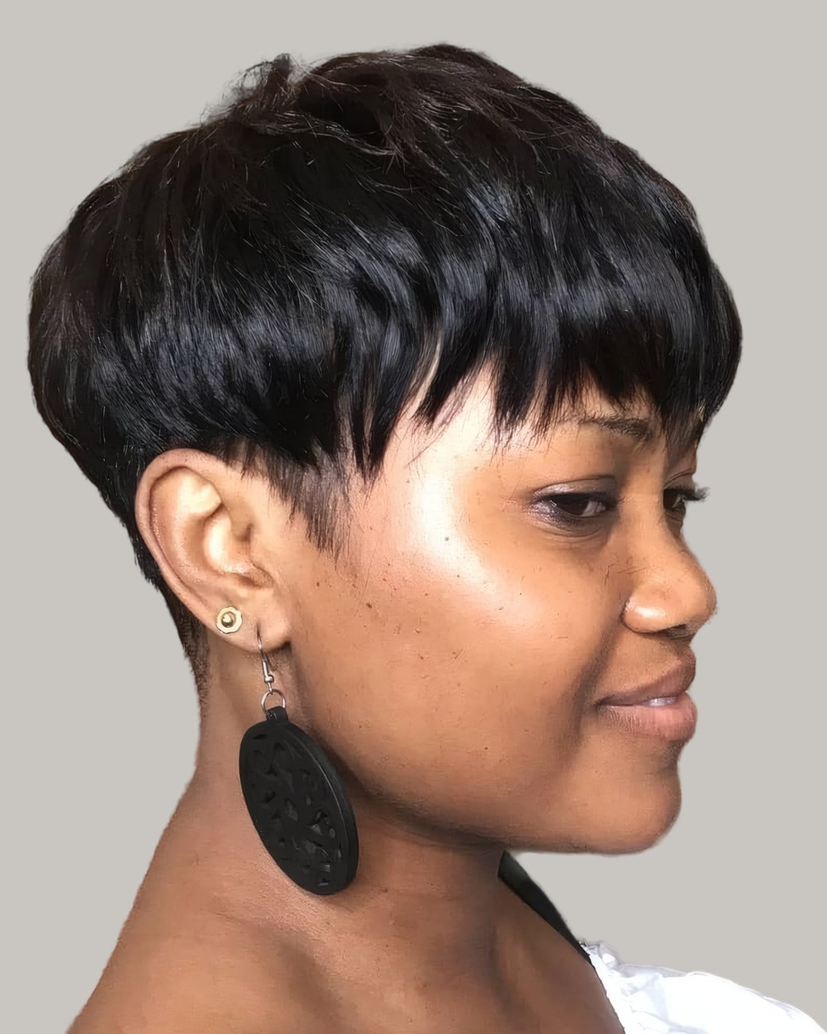 Woman with a black bowl cut and a large earring, seen from the side
