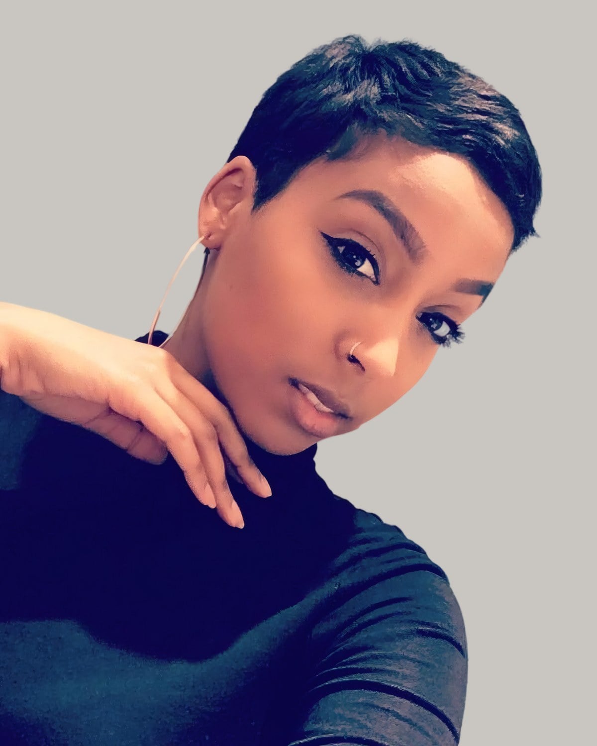 Woman with a very short black side-parted pixie, hand at her neck