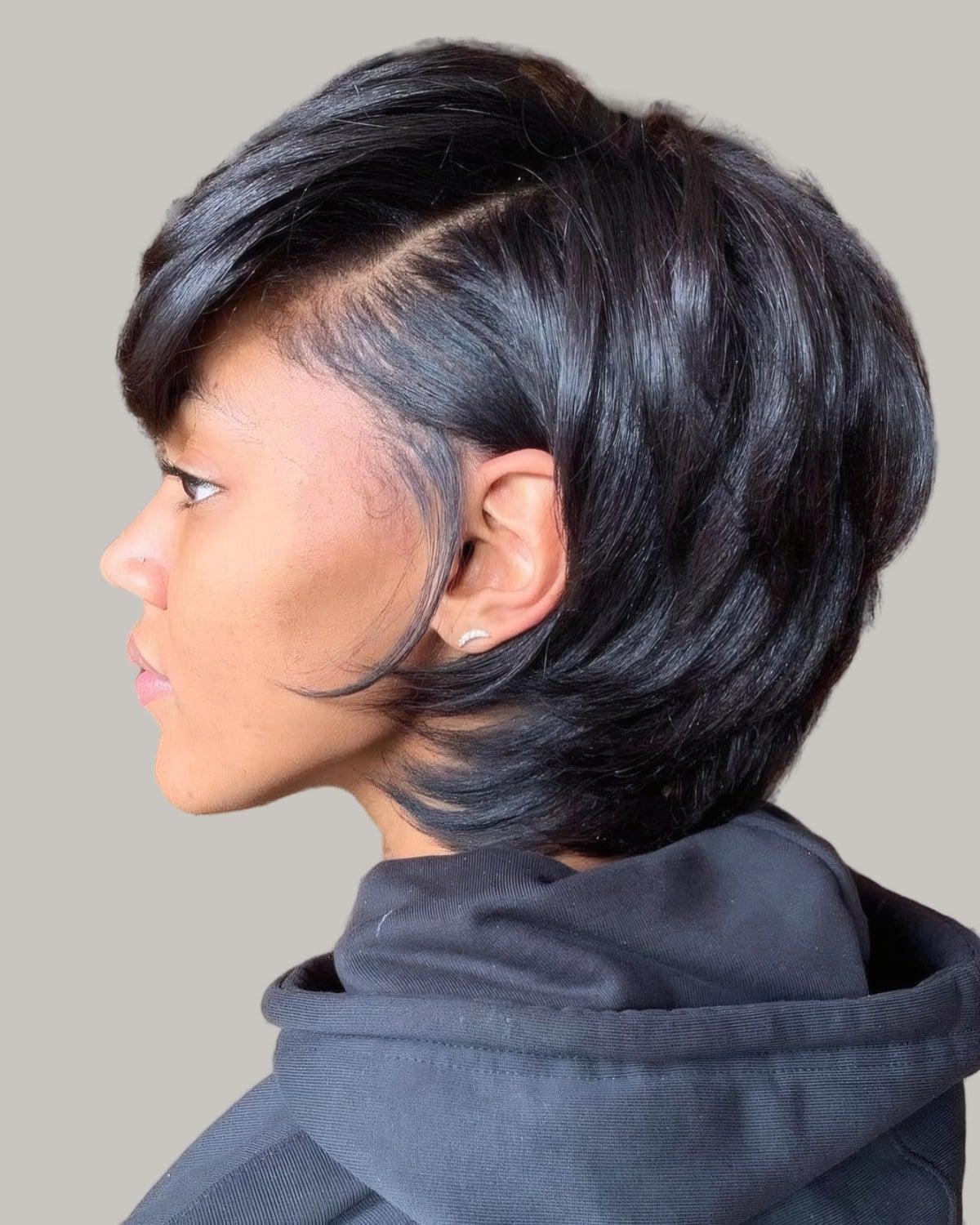Woman with a side-parted pixie bob seen from the side
