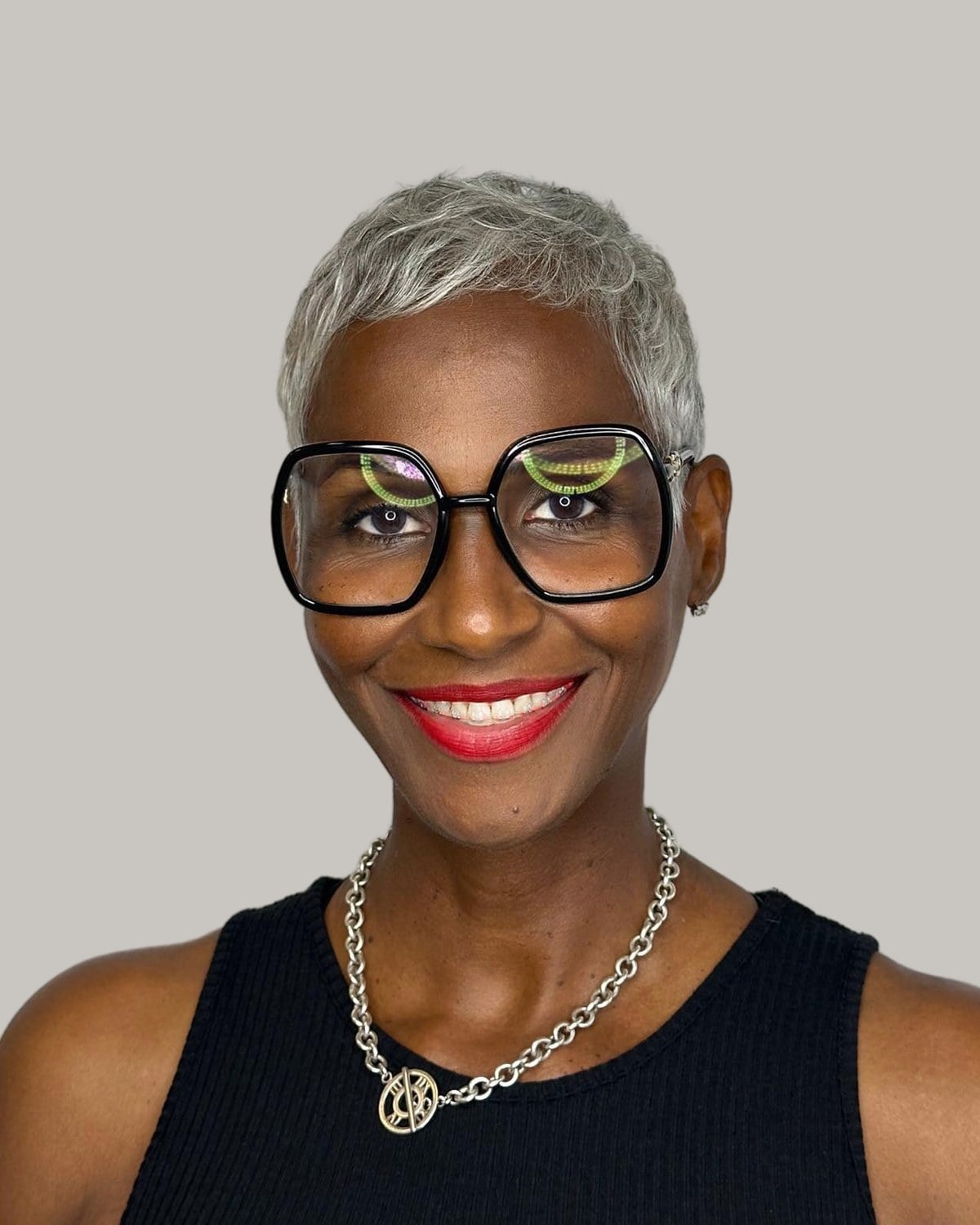 Smiling woman with a short gray pixie crop and oversized glasses
