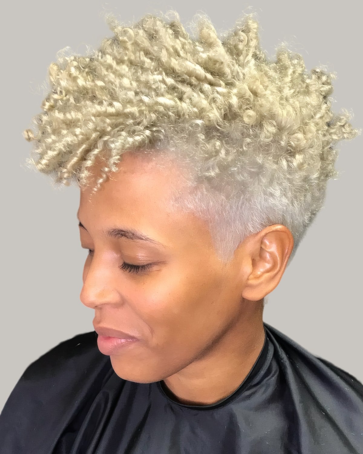 Woman with blonde twisted curls on top and a close taper at the side