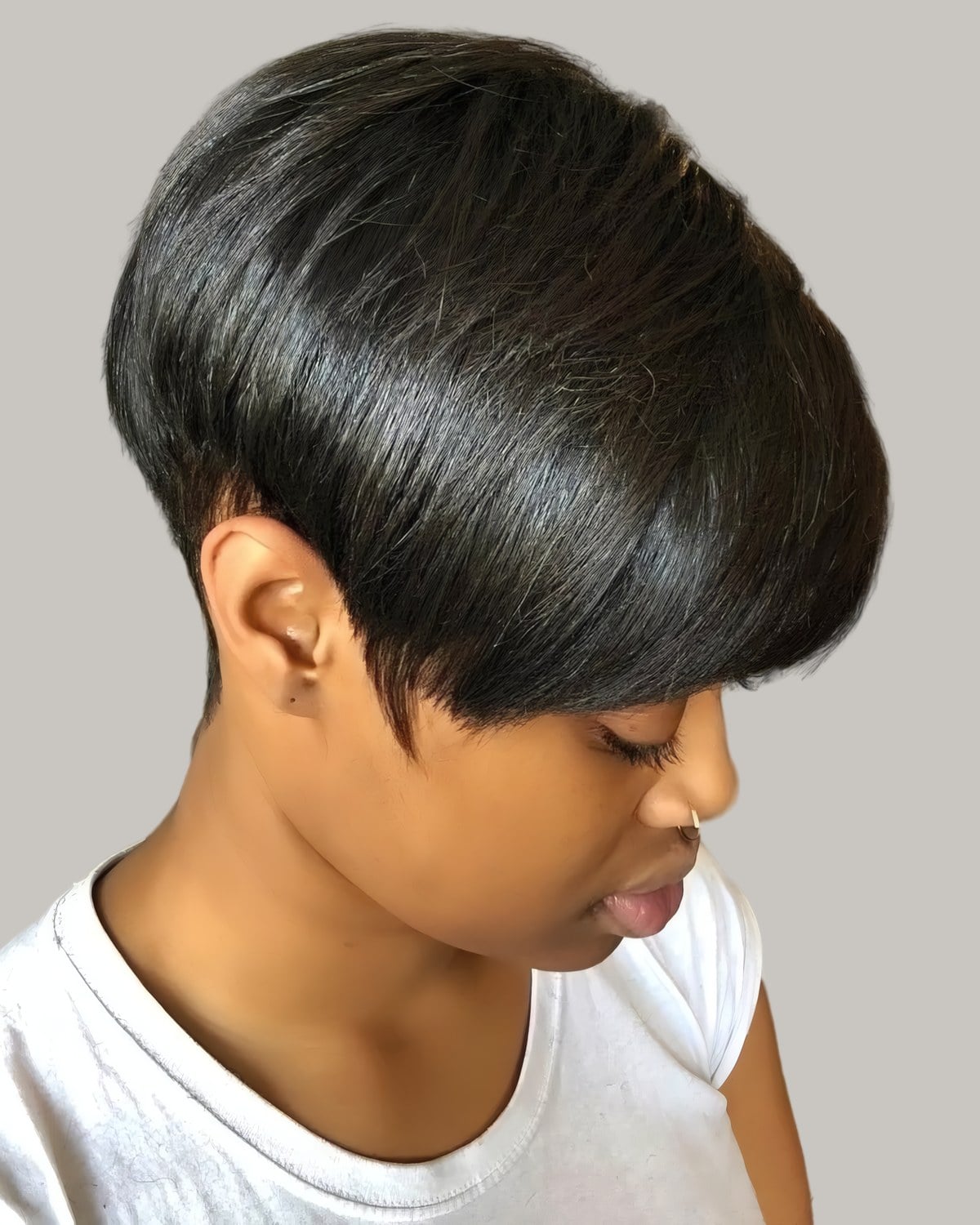 Woman with a glossy black tapered pixie, the top falling forward in one sleek layer