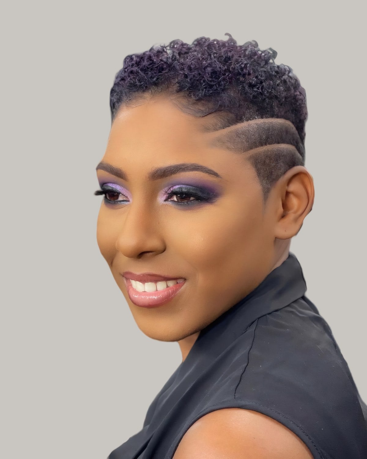 Smiling woman with a short tapered TWA and shaved lines at the side