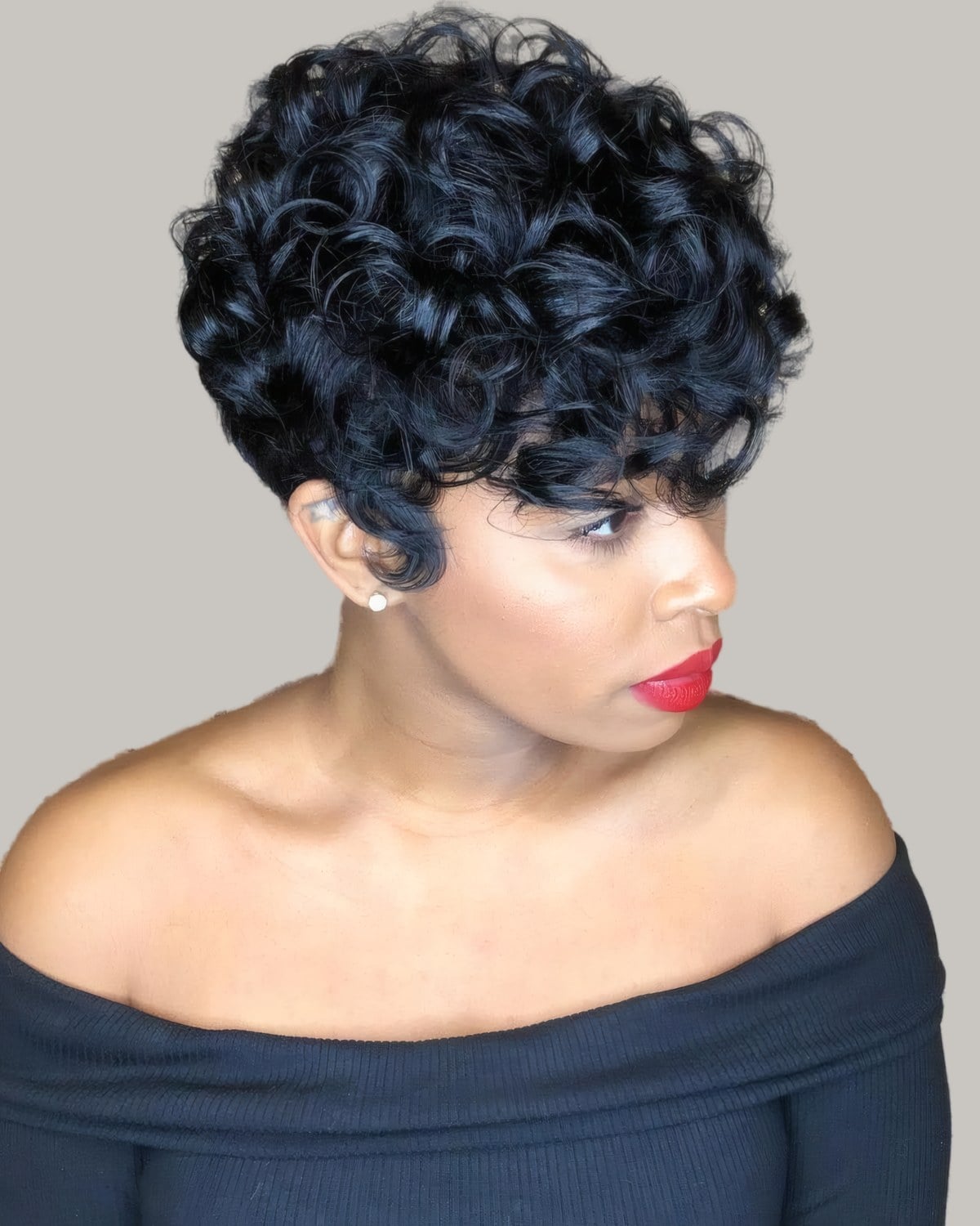 Woman with a short black pixie of glossy curls, off-the-shoulder top