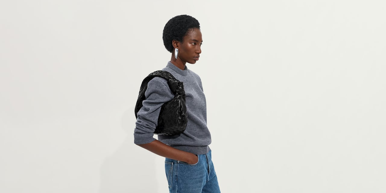Woman wearing a black Bottega Veneta Jodie bag on her shoulder - bottega veneta jodie alternatives - Luxe Digital