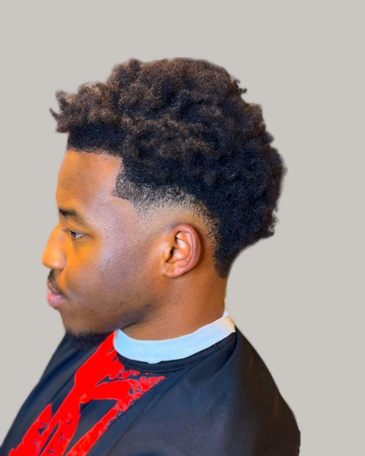 Man with a full afro top and a burst fade, seen in profile