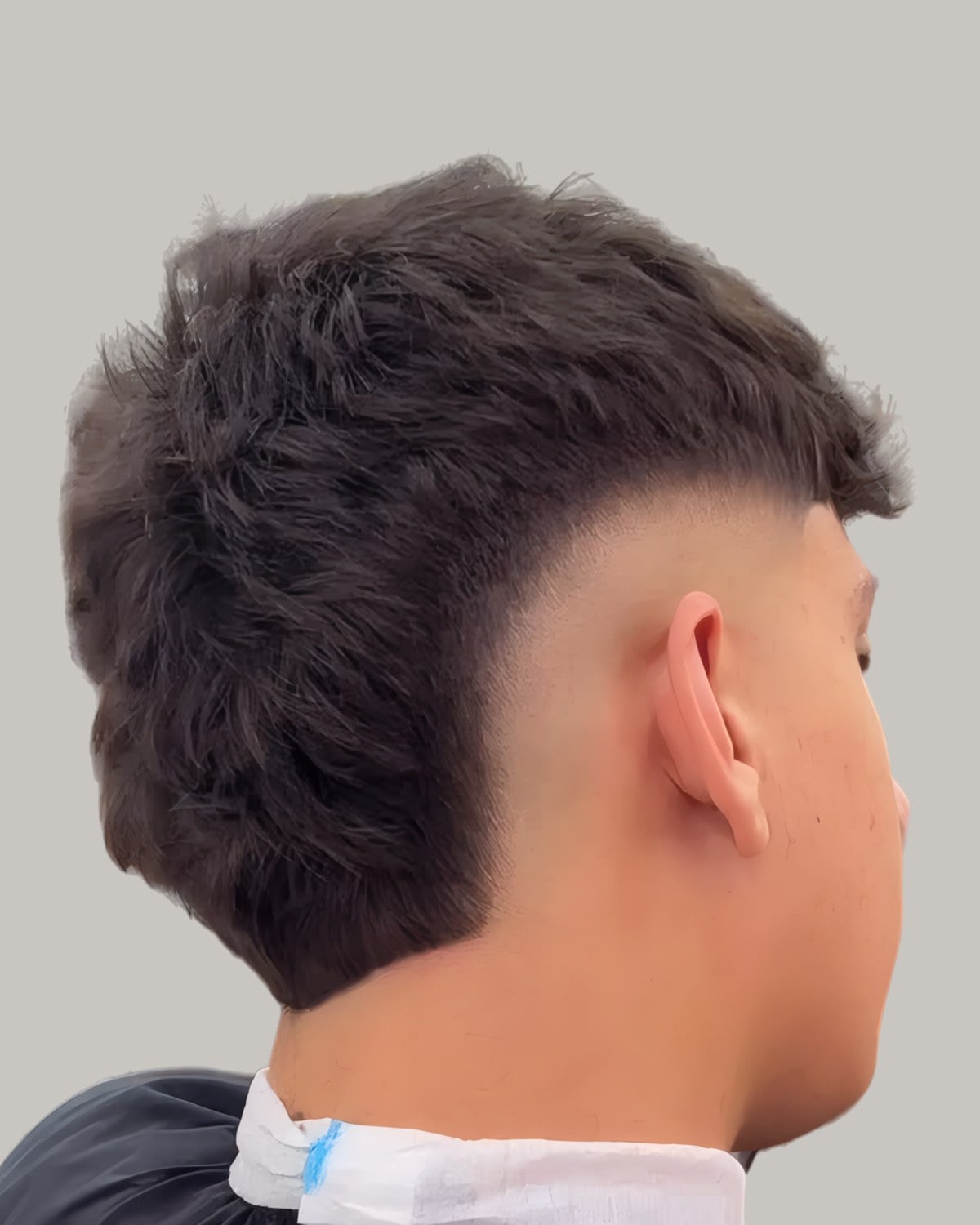 Man with a dark shaggy mullet and a burst fade, seen from behind