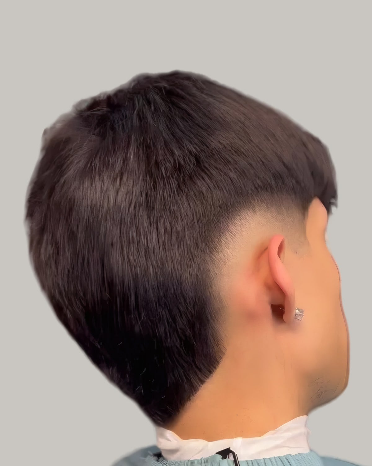 Man with a straight dark mullet and a burst fade, seen from behind