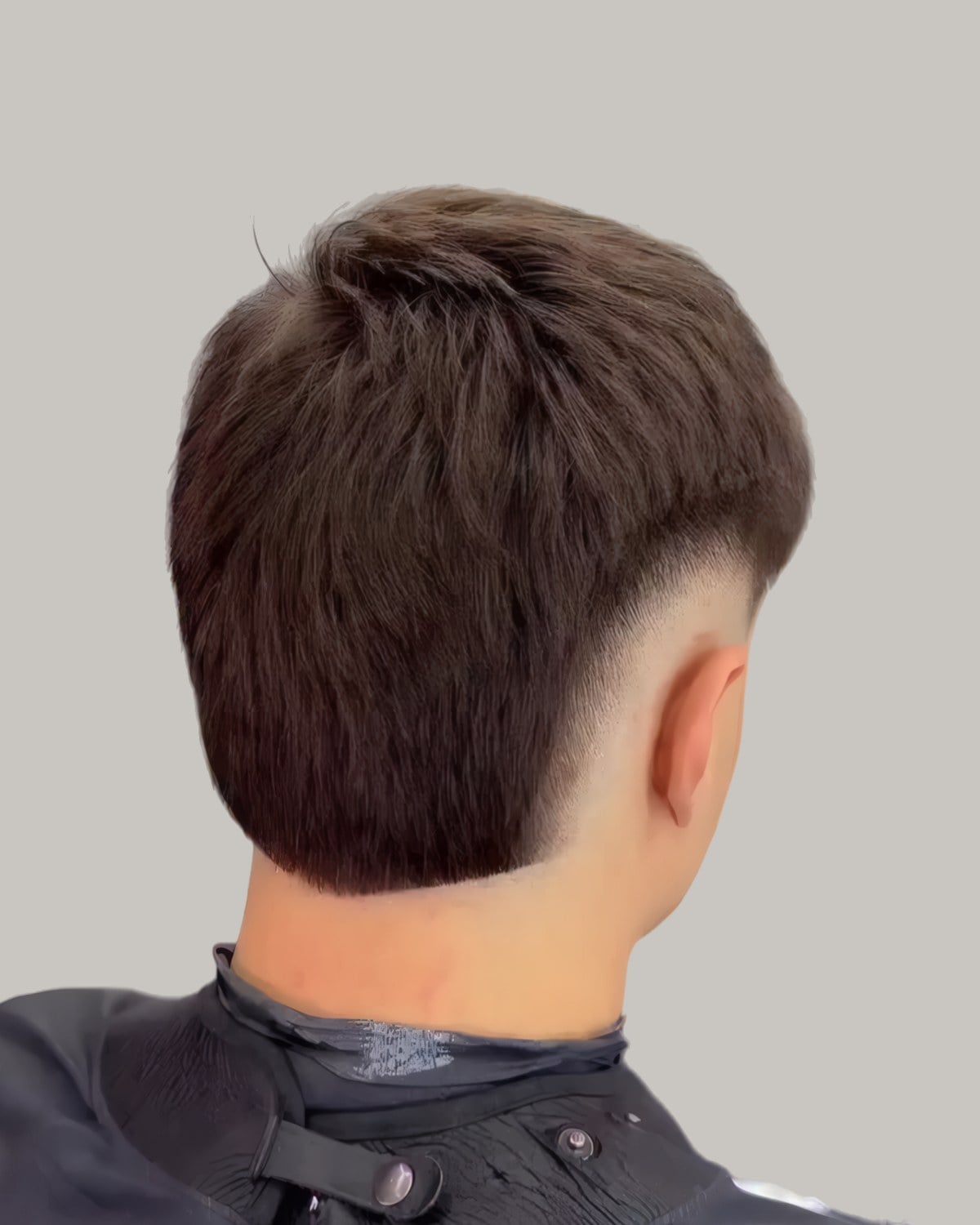 Man with a dark straight haircut and a mid burst fade, seen from behind