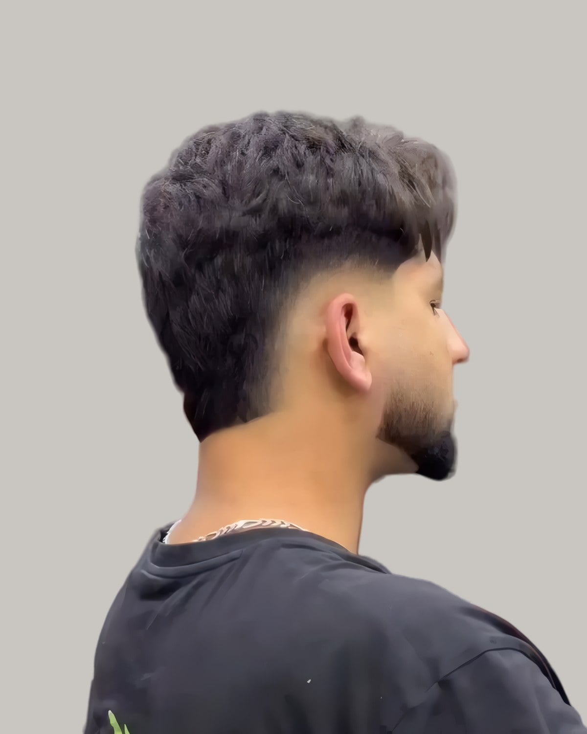Bearded man with a textured top and a burst fade, seen from behind at an angle
