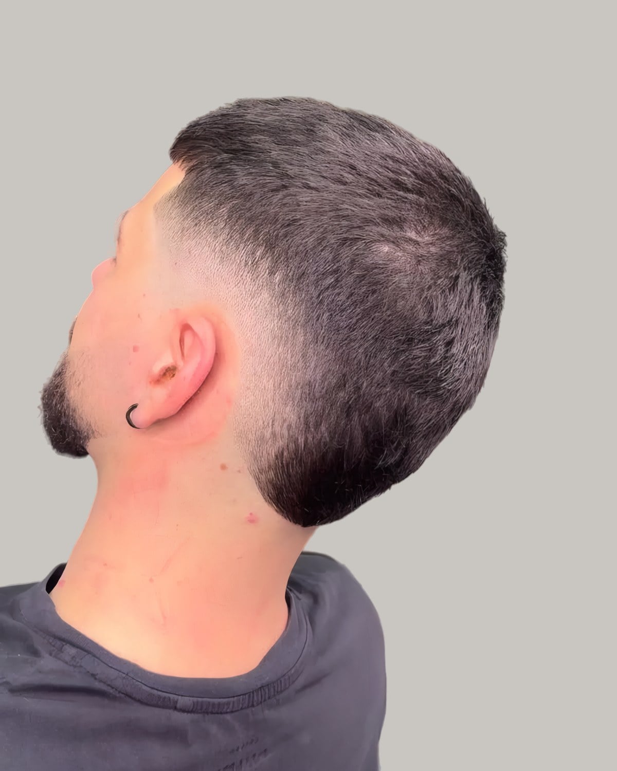 Bearded man with a short textured top and a burst fade, seen from behind at an angle