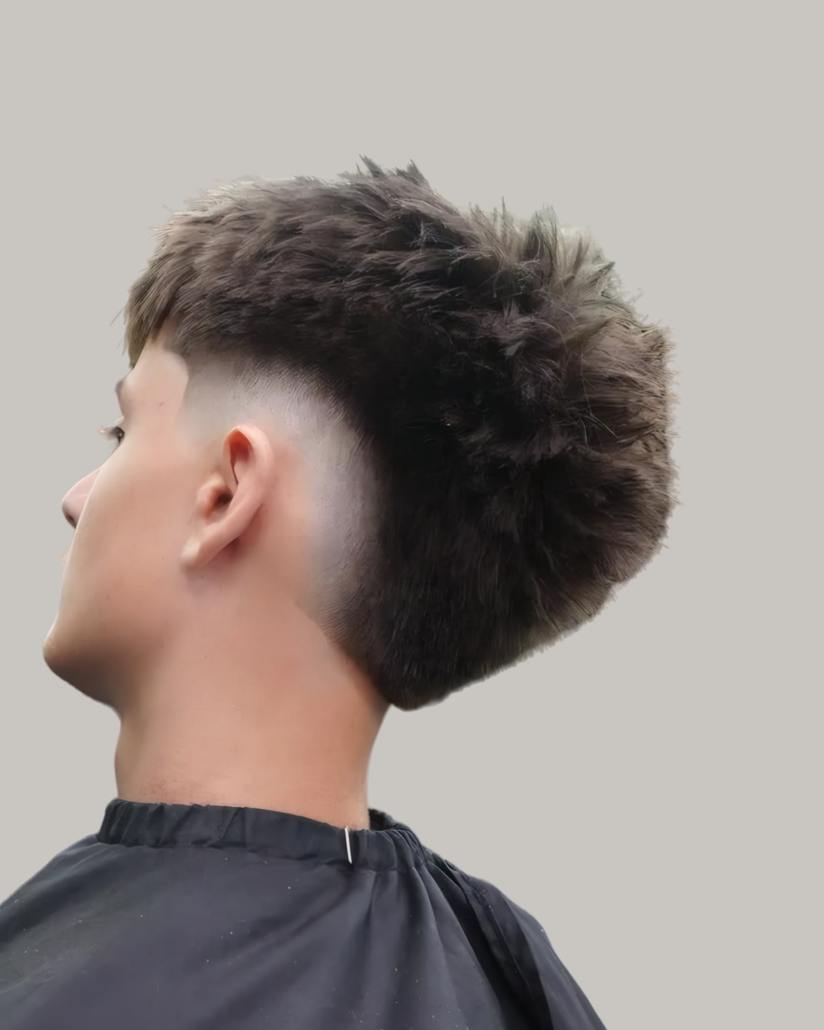 Man with a spiky textured top and a burst fade, seen from behind at an angle