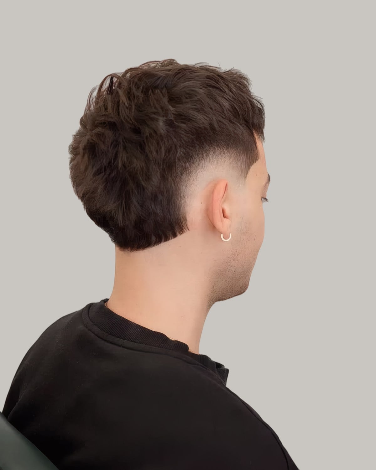 Man with a brown wavy crop and a burst fade, seen from behind