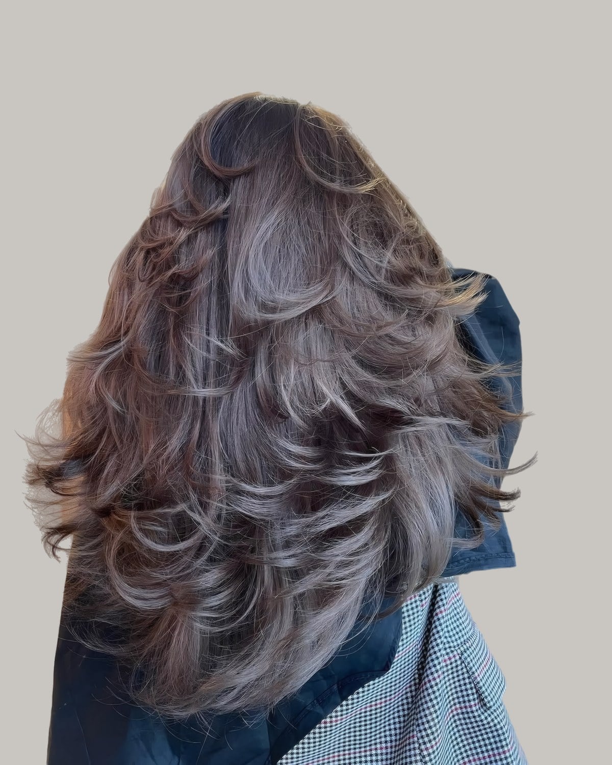 Back view of long, thick dark hair with silvery highlights and curled layers