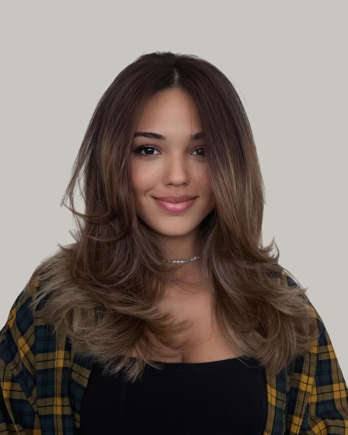 Woman in a plaid shirt with long brown hair curled into face-framing layers