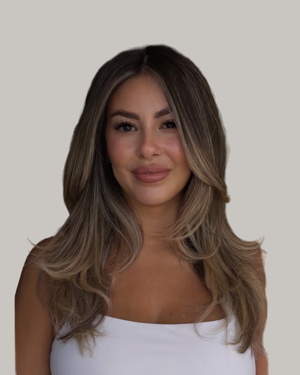 Woman in a white top with long, highlighted face-framing layers and a middle part
