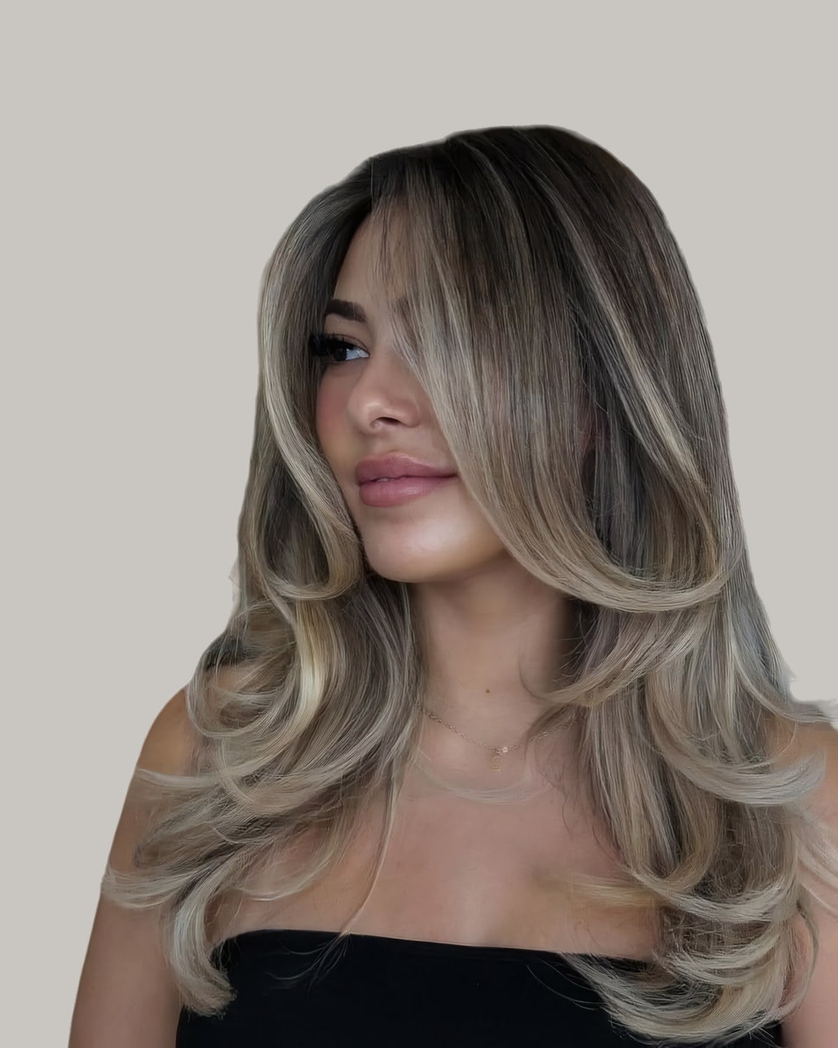 Woman looking to the side, long highlighted hair curled away from her face