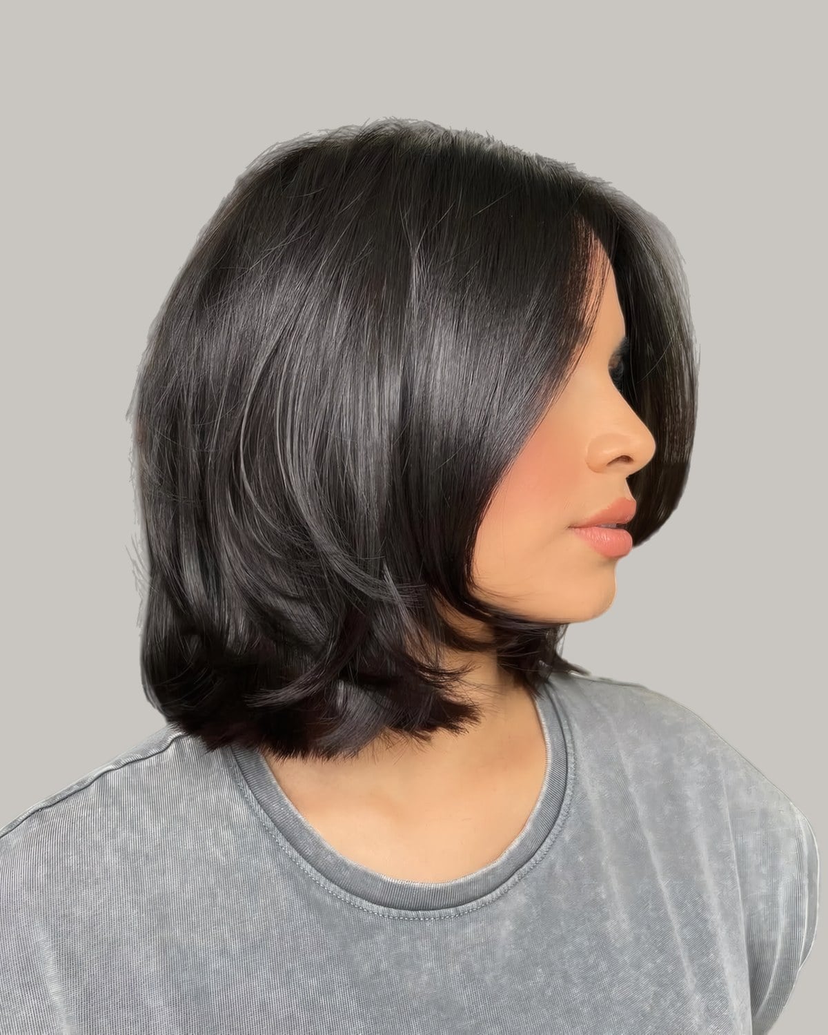 Woman in a gray T-shirt with a straight black lob, seen from the side